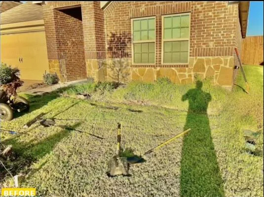 Same foundation bed before landscaping, overgrown grass and no defined planting area